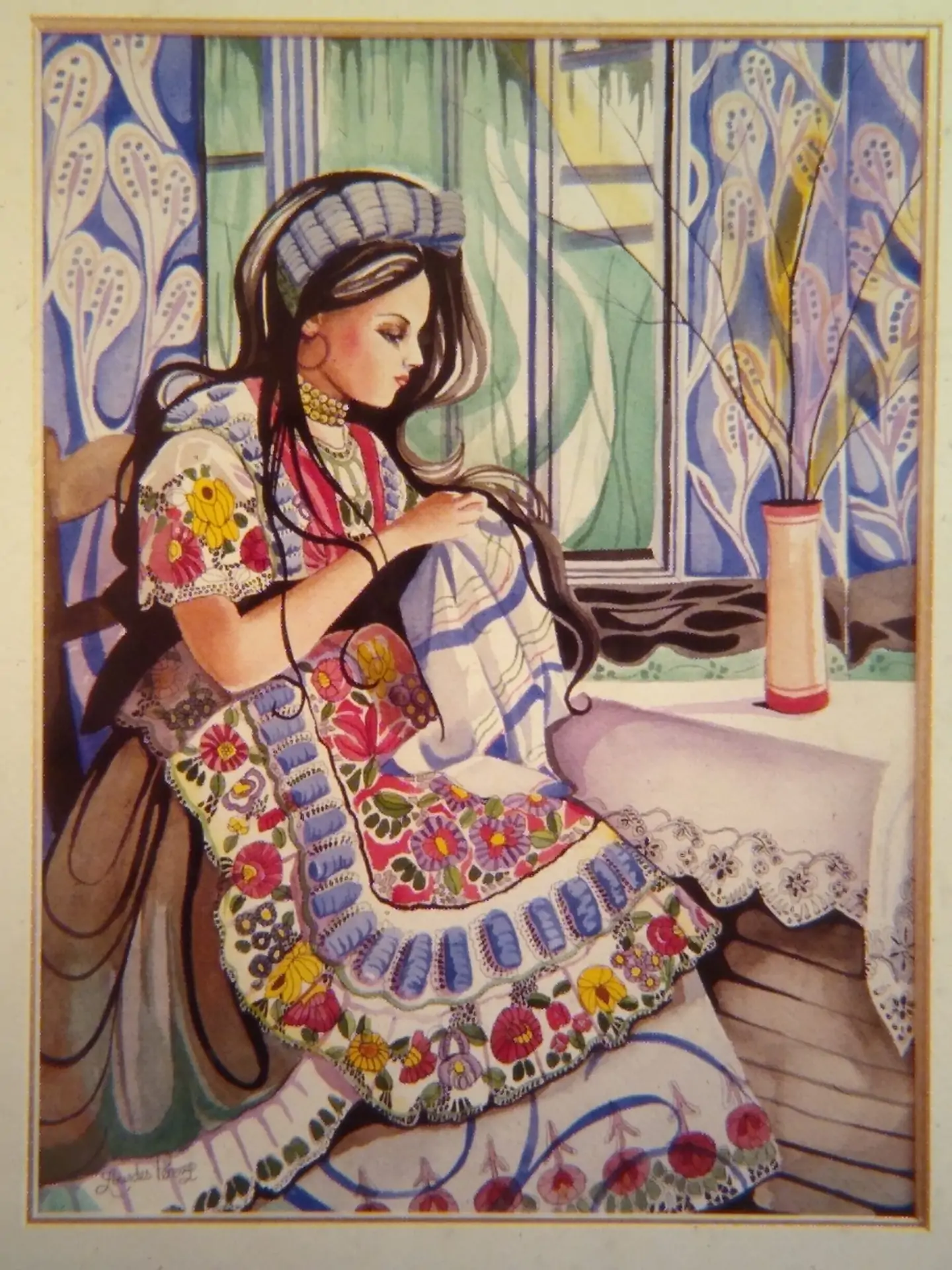 A woman with long, dark, wavy hair sits at a table holding a cloth. The woman's dress, the cloth and the background wallpaper are all very ornate and colorful. A thin vase on the table holds a few branches completely devoid of leaves or flowers.